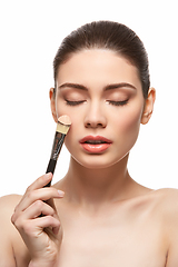 Image showing girl applying foundation on face isolated on white