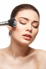 Image showing girl applying powder on face isolated on white