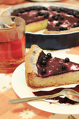 Image showing Piece of pie with bilberry on the plate and cup of tea