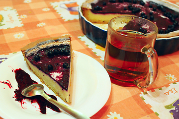 Image showing Piece of pie with bilberry on the plate and cup of tea