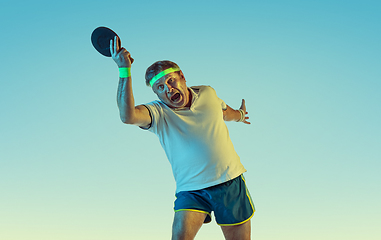 Image showing Senior man playing table tennis in sportwear on gradient background and neon light