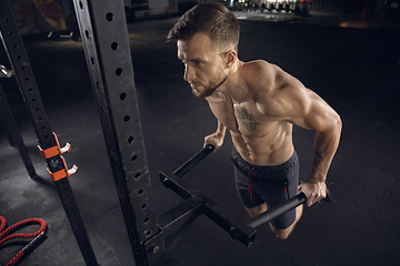 Image showing Young healthy male athlete doing exercises in the gym