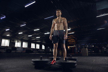 Image showing Young healthy male athlete doing exercises in the gym