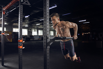 Image showing Young healthy male athlete doing exercises in the gym