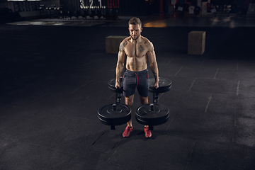 Image showing Young healthy male athlete doing exercises in the gym