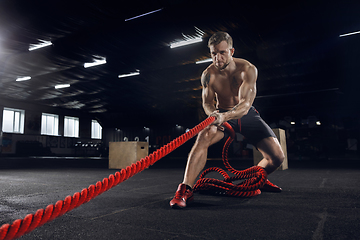 Image showing Young healthy male athlete doing exercises in the gym