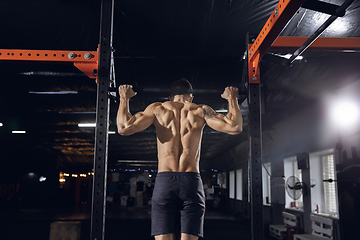 Image showing Young healthy male athlete doing exercises in the gym