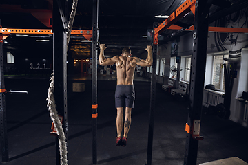 Image showing Young healthy male athlete doing exercises in the gym