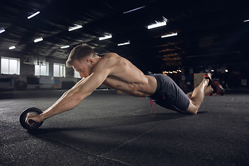 Image showing Young healthy male athlete doing exercises in the gym