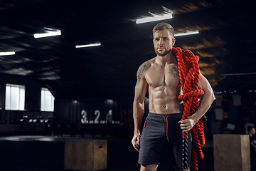 Image showing Young healthy male athlete doing exercises in the gym