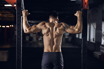 Image showing Young healthy male athlete doing exercises in the gym