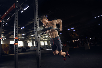 Image showing Young healthy male athlete doing exercises in the gym