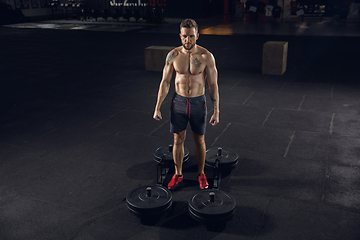 Image showing Young healthy male athlete doing exercises in the gym