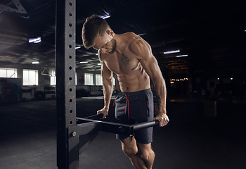 Image showing Young healthy male athlete doing exercises in the gym