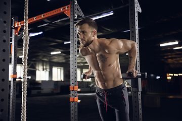 Image showing Young healthy male athlete doing exercises in the gym