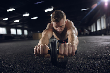 Image showing Young healthy male athlete doing exercises in the gym