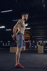 Image showing Young healthy male athlete doing exercises in the gym