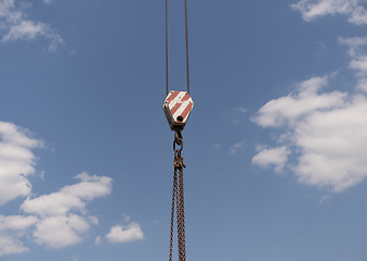 Image showing Crane hook with red and white stripes hanging, blue sky in background