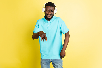 Image showing Young African man in headphones isolated over yellow studio background with copyspace.