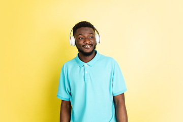 Image showing Young African man in headphones isolated over yellow studio background with copyspace.