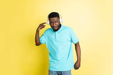 Image showing Young African man in headphones isolated over yellow studio background with copyspace.