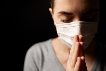 Image showing sick young woman in protective face mask praying