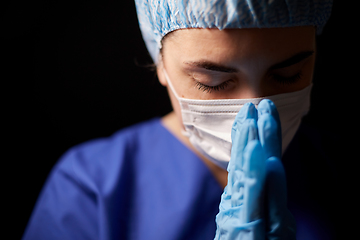 Image showing female doctor or nurse in face mask praying