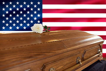 Image showing white rose on wooden coffin over flag of america