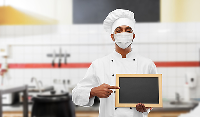 Image showing chef in face mask with chalkboard at kitchen