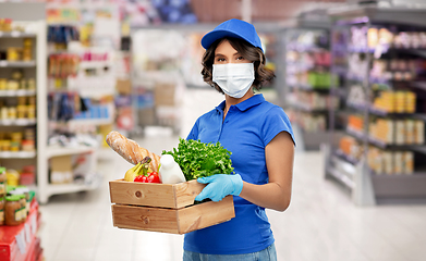 Image showing delivery girl in mask with food in box at store