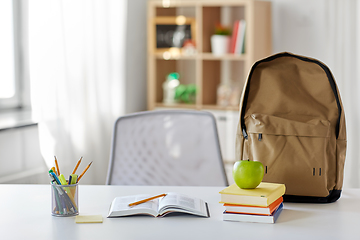 Image showing books, apple and school supplies on table at home