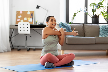 Image showing african american woman stretching arm at home