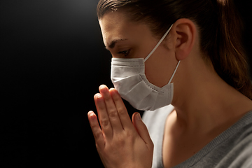 Image showing sick young woman in protective face mask praying