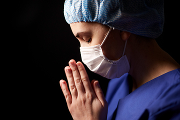 Image showing female doctor or nurse in face mask praying