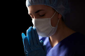 Image showing female doctor or nurse in face mask praying