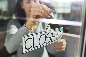 Image showing woman hanging banner with closed word on door