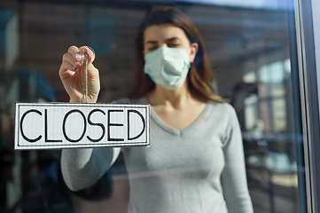 Image showing woman in mask hanging banner closed on door