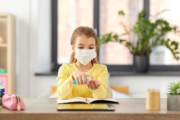 Image showing sick girl in mask with hand sanitizer at home