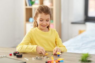 Image showing happy girl playing with robotics kit at home