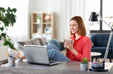 Image showing woman with laptop drinking coffee at home office