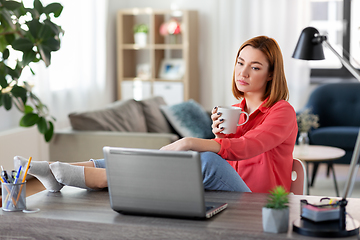 Image showing woman with laptop drinking coffee at home office