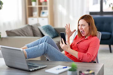 Image showing angry woman with smartphone at home office