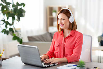 Image showing woman in headphones with laptop working at home