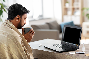 Image showing sick young man in blanket drinking hot tea at home