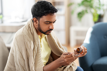 Image showing sick man pouring medication from bottle to spoon