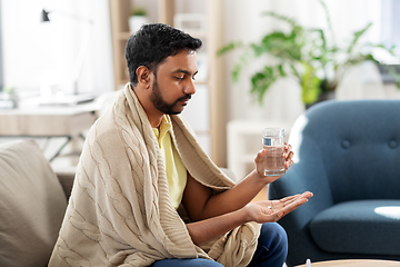 Image showing sick man with medicine and glass of water at home