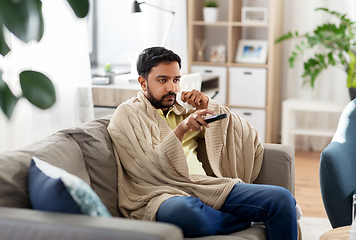 Image showing sick man with paper tissue and tv remote at home