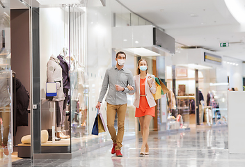 Image showing couple in medical masks with shopping bags in mall