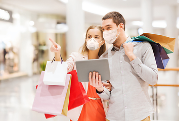 Image showing couple in masks with tablet pc in shopping mall