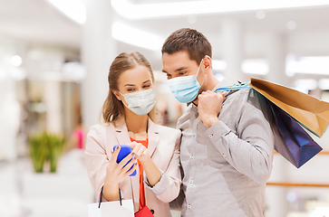Image showing couple in masks with smartphone in shopping mall